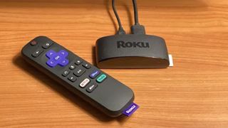 Roku Express 4K Plus on a wooden surface.