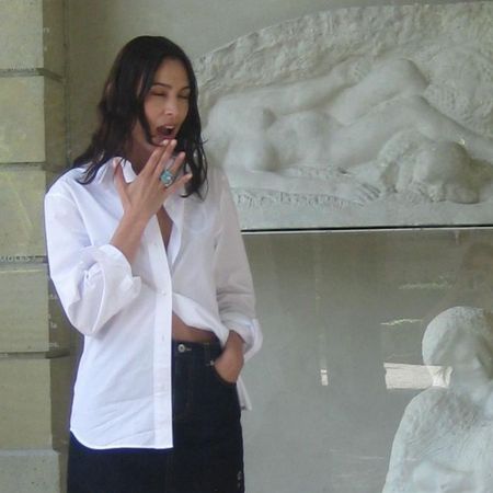 Alexa Chung wears a black denim miniskirt with silver bow heels and a white cotton button-down shirt.