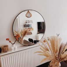 room with round mirror and white vase 