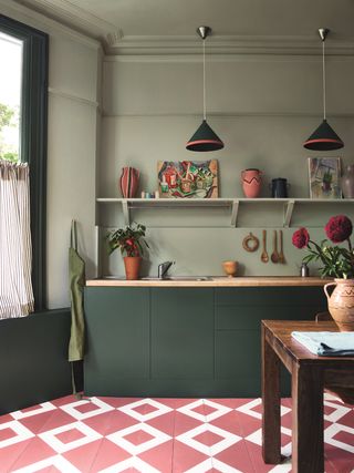 Green kitchen with a pink patterned floor and open shelves