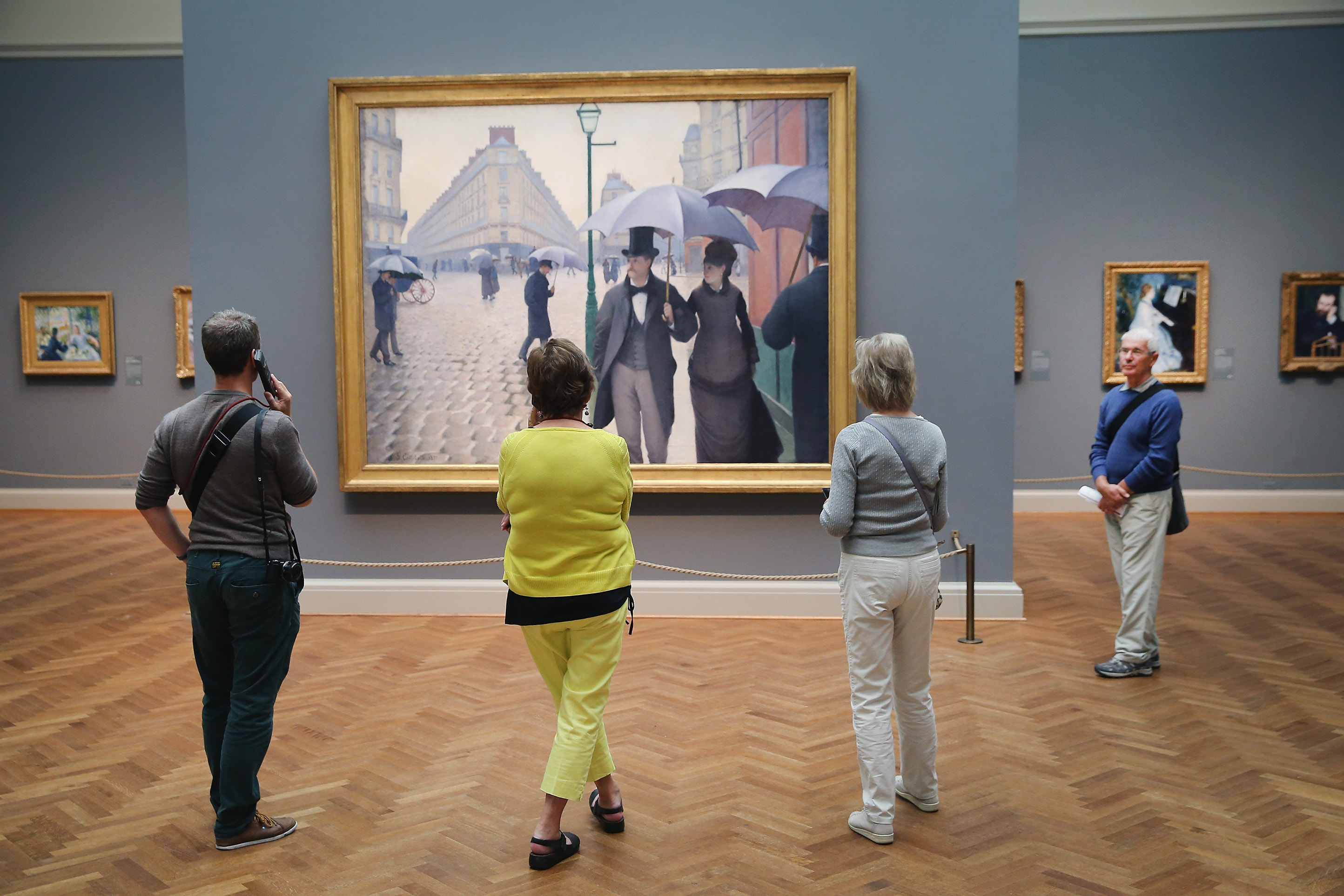 People at the Art Institute of Chicago look at "Paris Street; Rainy Day" by Gustave Caillebotte