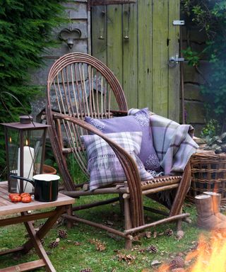 armchair with cushions and throws next to a fire pit
