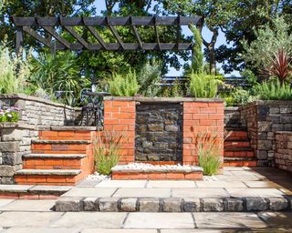 levelled garden with pergola and wall water feature
