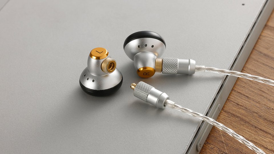 Sivga M260 HiFi wired earbuds in silver on the edge of a laptop