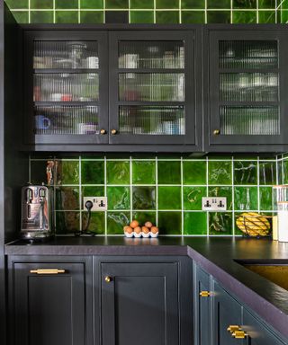 A Victorian industrial-style kitchen green glazed tiles and black cabinetry