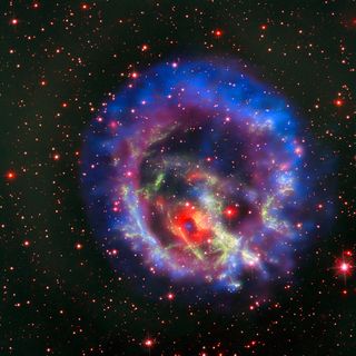 The new composite image of neutron star E0102, released on May 23, combines data from NASA's Chandra X-Ray Observatory (seen in blue and purple), the Multi Unit Spectroscopic Explorer instrument on the European Southern Observatory's Very Large Telescope in Chile (in bright red) and the Hubble Space Telescope (in dark red and green).
