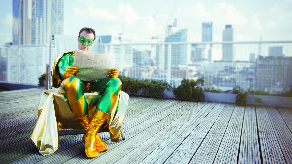 A super hero sits on a roof top reading the news.