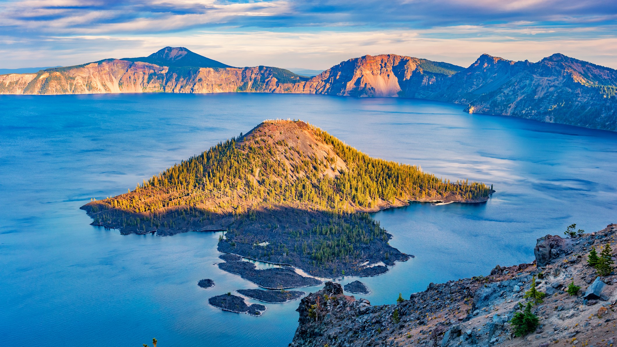 un gran lago azul con una pequeña isla cubierta de árboles.