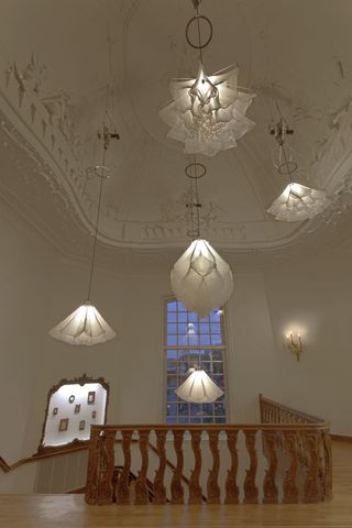 Five white silk lights modelled on flowers hang from an ornate, domed ceiling