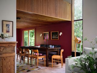 dining room with burgundy paint, timber ceiling, blue banquette seat and timber chairs around dining table