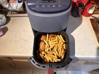 Fries and chicken nuggets in an air fryer basket