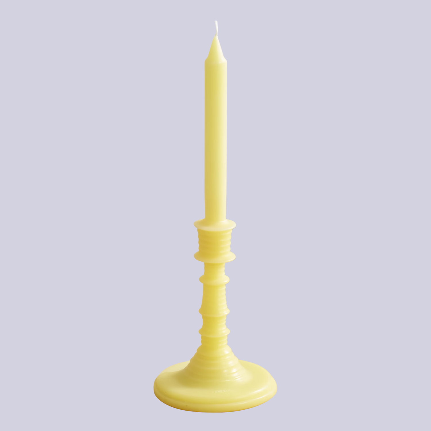 A tapered yellow candle against a lilac backdrop