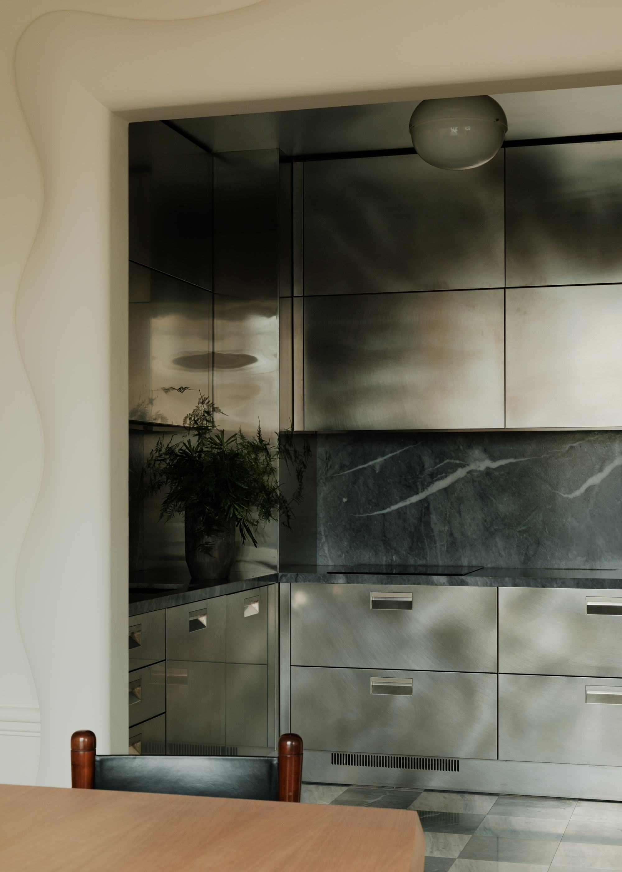 a dark gray stainless steel kitchen with a marble backsplash and checkerboard floors