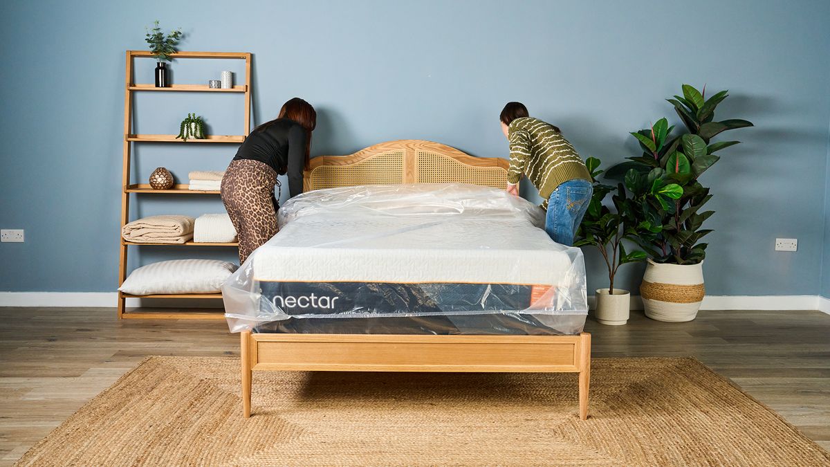 Two Tom's Guide mattress testers pulling the plastic wrapping off a new Nectar Ultra Hybrid mattress