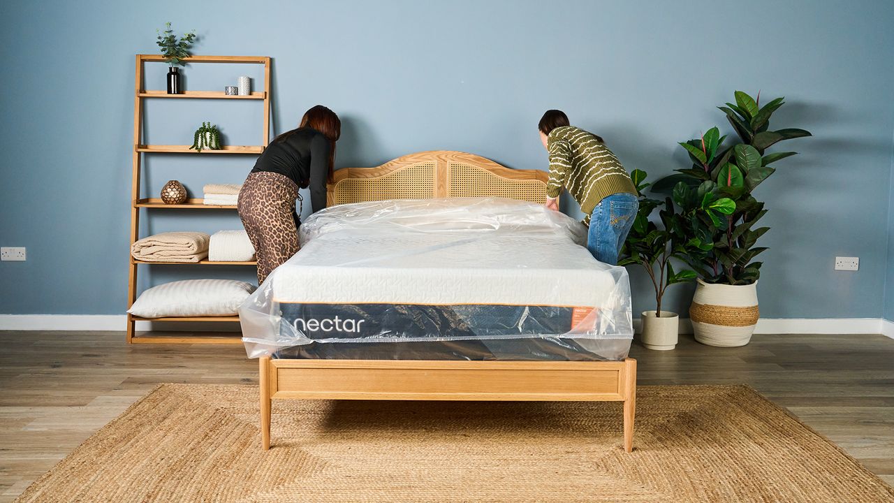 Two Tom's Guide mattress testers pulling the plastic wrapping off a new Nectar Ultra Hybrid mattress