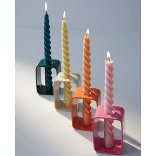 four colorful candle holders in open box shapes holding twisted taper candles