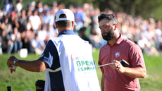 Jon Rahm hands his putter to his caddie