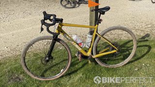 A yellow Santa Cruz gravel bike leaning against a signpost