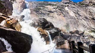 High debit Wapama Falls flowing over the footbridge and creating hazardous conditions for crossing
