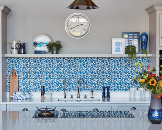Modern kitchen ideas with blue and white tiles in a backsplash below a pale gray shelf.