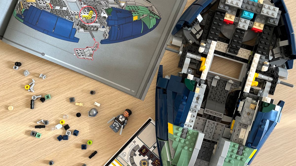 Lego Star Wars UCS Jango Fett&rsquo;s Firespray-Class Starship (75409) mid-build on wooden tabletop next to lots of Lego pieces and an instruction booklet