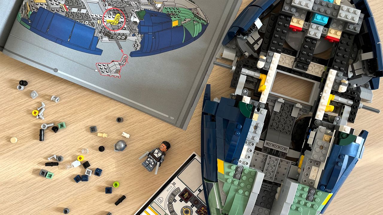 Lego Star Wars UCS Jango Fett&rsquo;s Firespray-Class Starship (75409) mid-build on wooden tabletop next to lots of Lego pieces and an instruction booklet