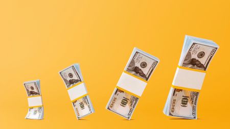 wads of 100 dollar bills on yellow background