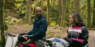 Preacher and Kaia sitting on motorbikes in the woods.