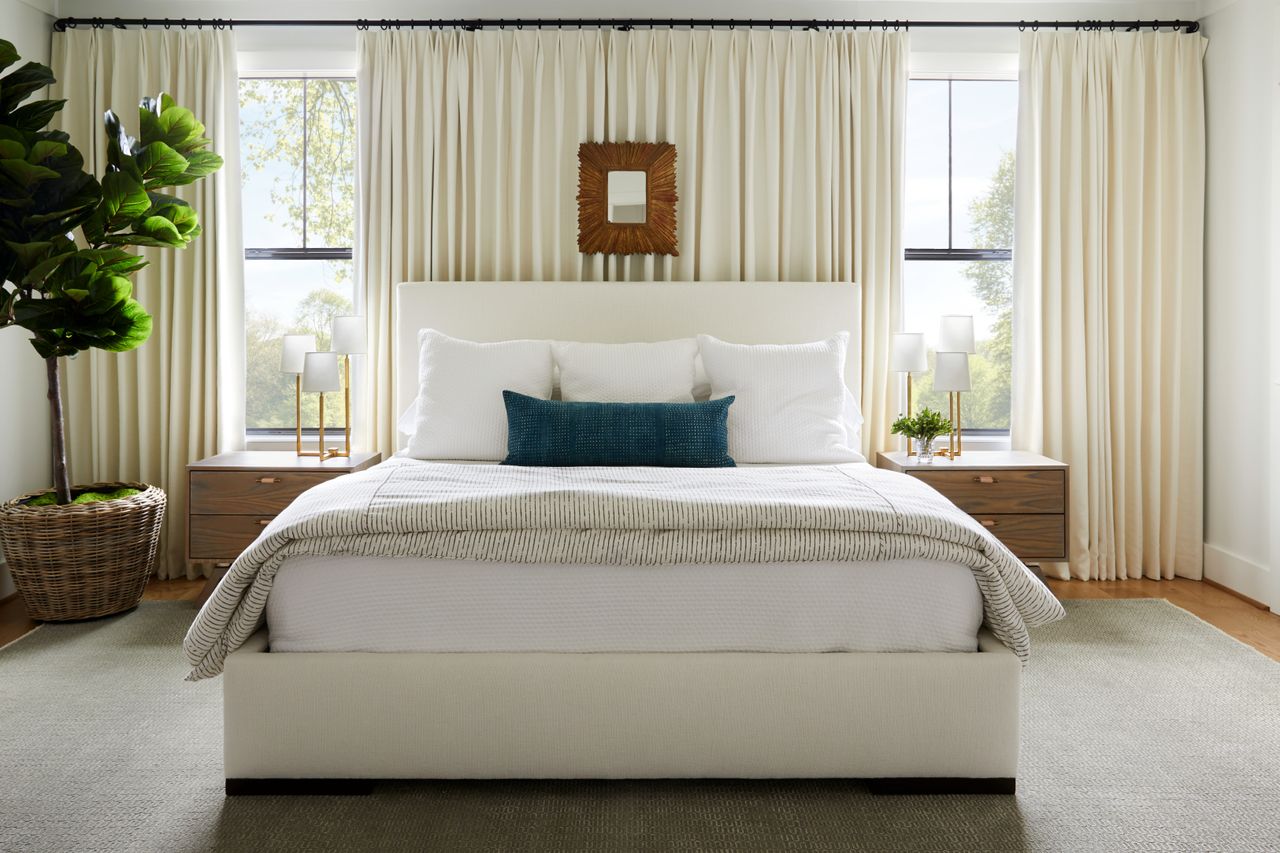 pale bedroom with wall to wall curtains behind the bed