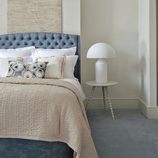 how to make a guest room look more expensive, blue and stone bedroom with blue carpet, stone artwork and throw, white bedding, white side table and lamp