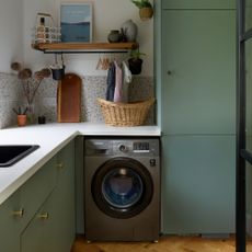 Green kitchen with white worktops and walls, and a grey washing machine