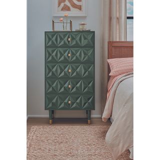 A credenza painted in dark green next to a bed