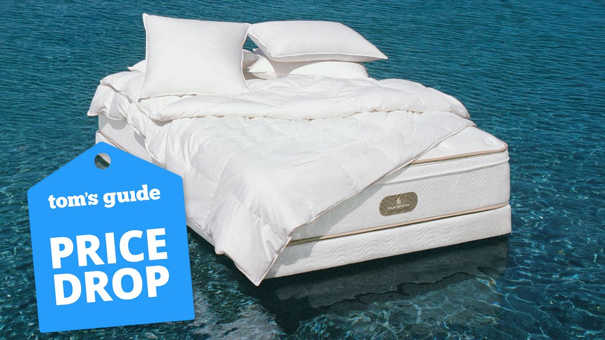 A white Four Seasons hotel mattress dressed with a white Four Seasons comforter and luxury bedding floats on a blue ocean