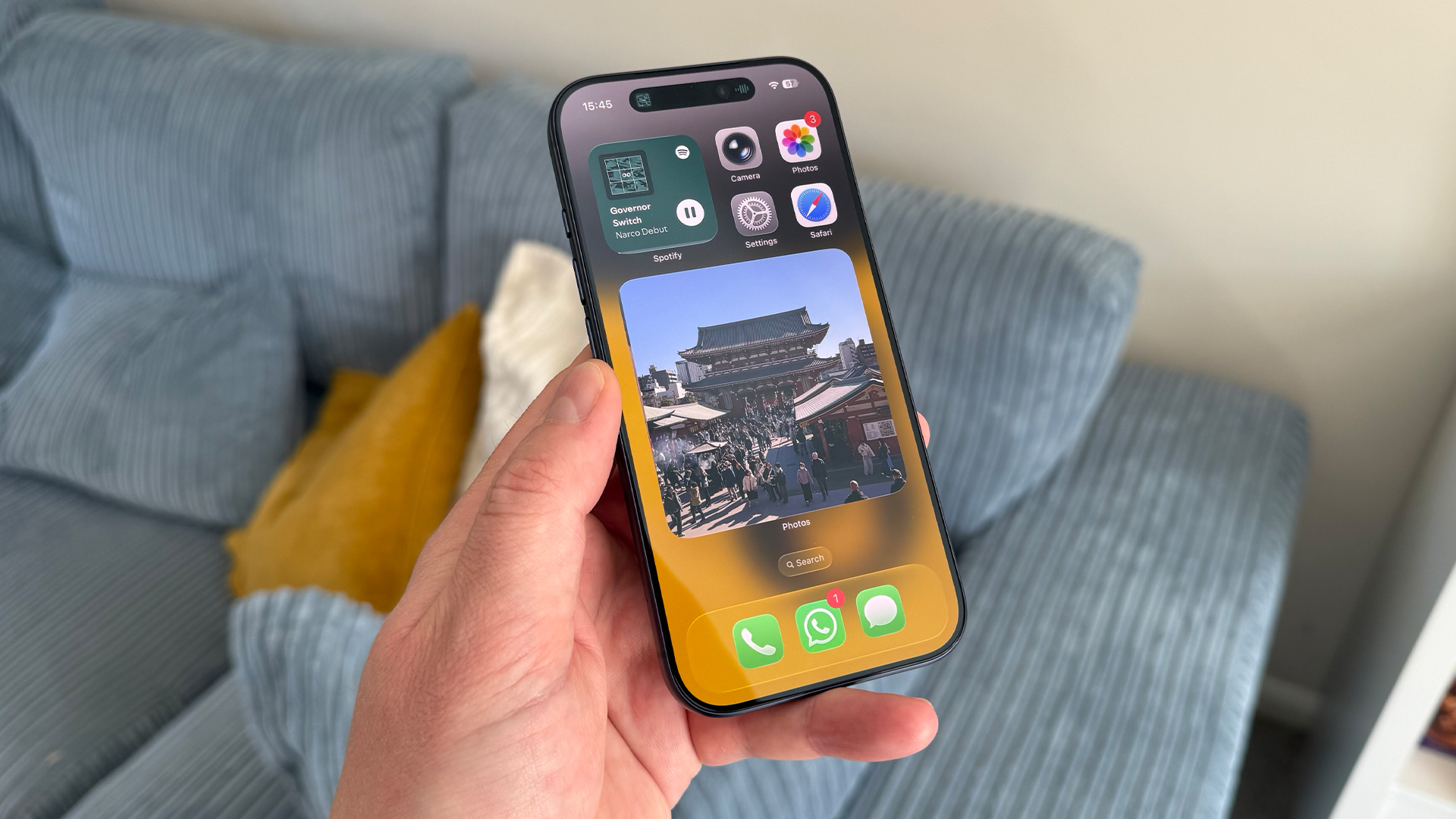 Apple iPhone 17 Pro smartphone held in hand above blue sofa
