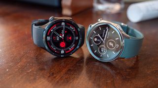 The OnePlus Watch 3 (left) and OnePlus Watch 2 (right) sitting atop a table with their watch faces visible