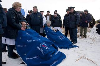 The Soyuz spacecraft crew smile for photographers after landing in Kazakhstan to end their six-month space mission.