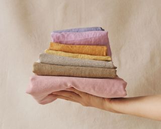 Arm holding pile of colorful folded linens