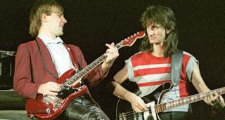 Rush's Alex Lifeson playing his red Sportscaster, flanked by Geddy Lee on a Rickenbacker bass