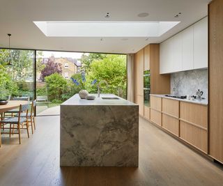 modern kitchen extension with wooden kitchen and sliding doors and roof lantern over modern stone kitchen island