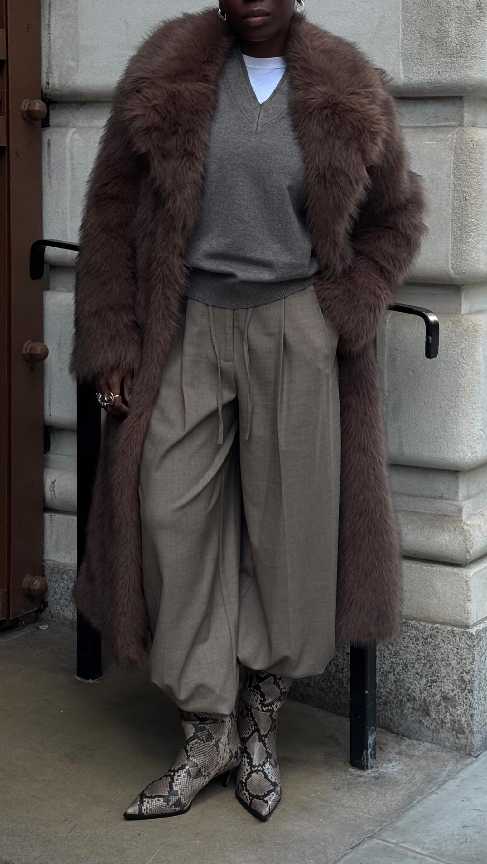 Street style photo of woman wearing a long fur coat.