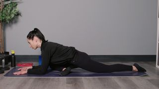 Sam performing pigeon pose in studio on mat