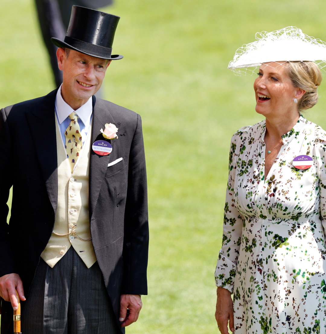 Duchess Sophie wearing a white hat and floral dress and Prince Edward in a top hat and suit smiling at Royal Ascot 
