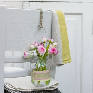 flowers in vessels hung on white chair
