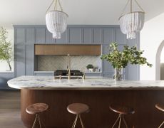 A modern kitchen with a curved marble island countertop