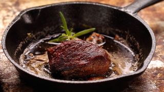 Cooked juicy steak cooking in a cast iron skillet
