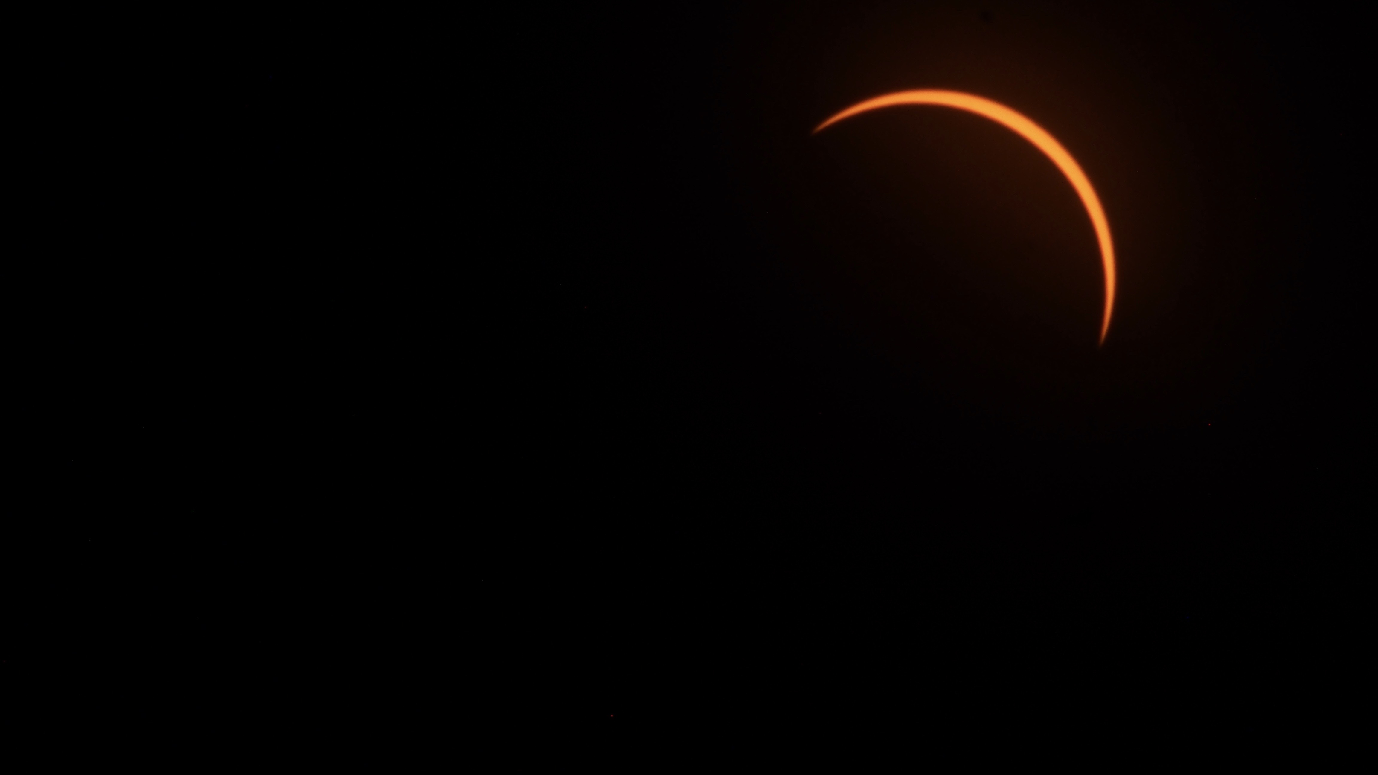 a yellow-orange crescent hangs top right in a sky of black.