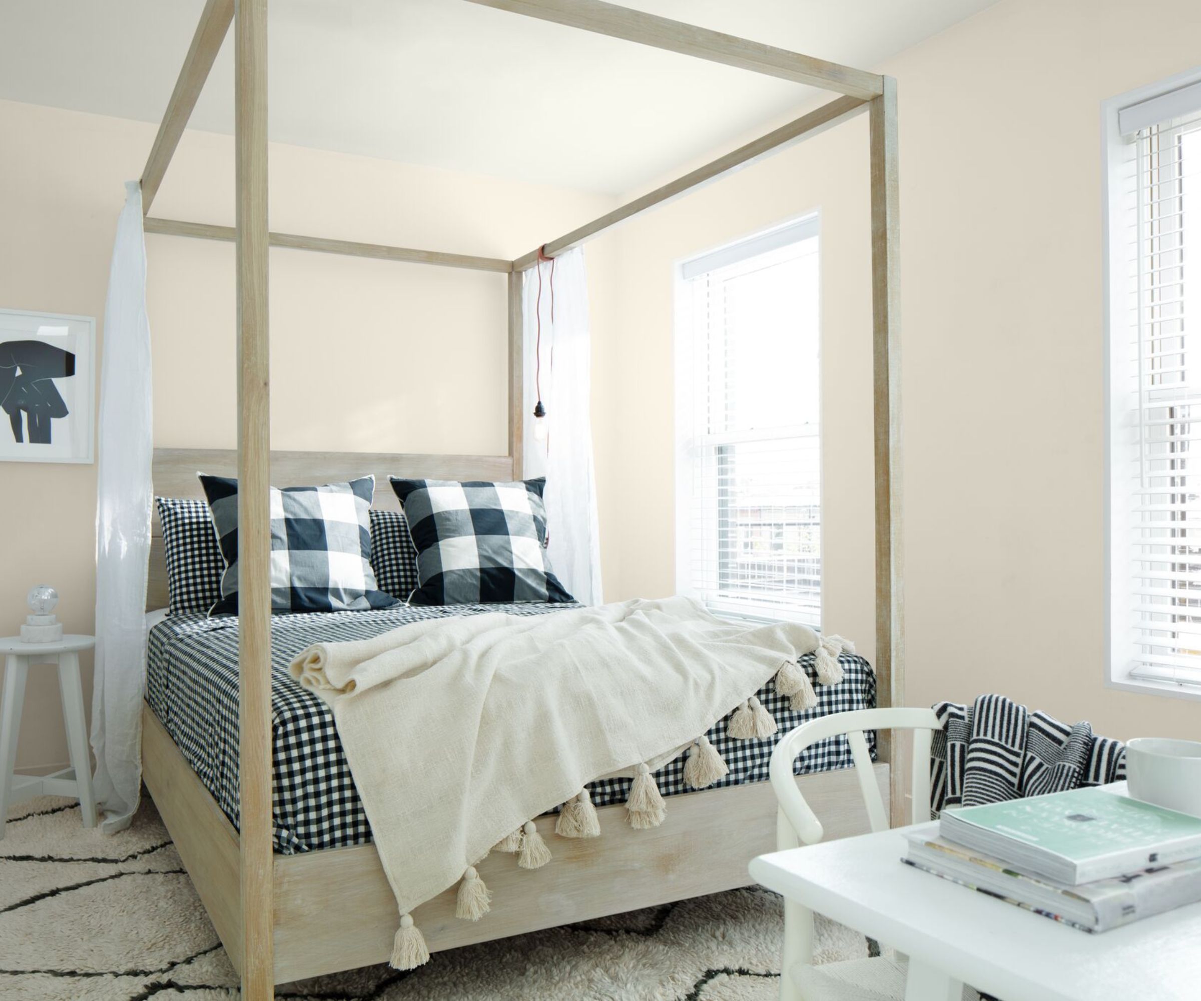 Guest bedroom painted in Collector's Item by Benjamin Moore, a modern wood four-poster bed, navy blue gingham bedding, a Berber cream rug, and a white desk.
