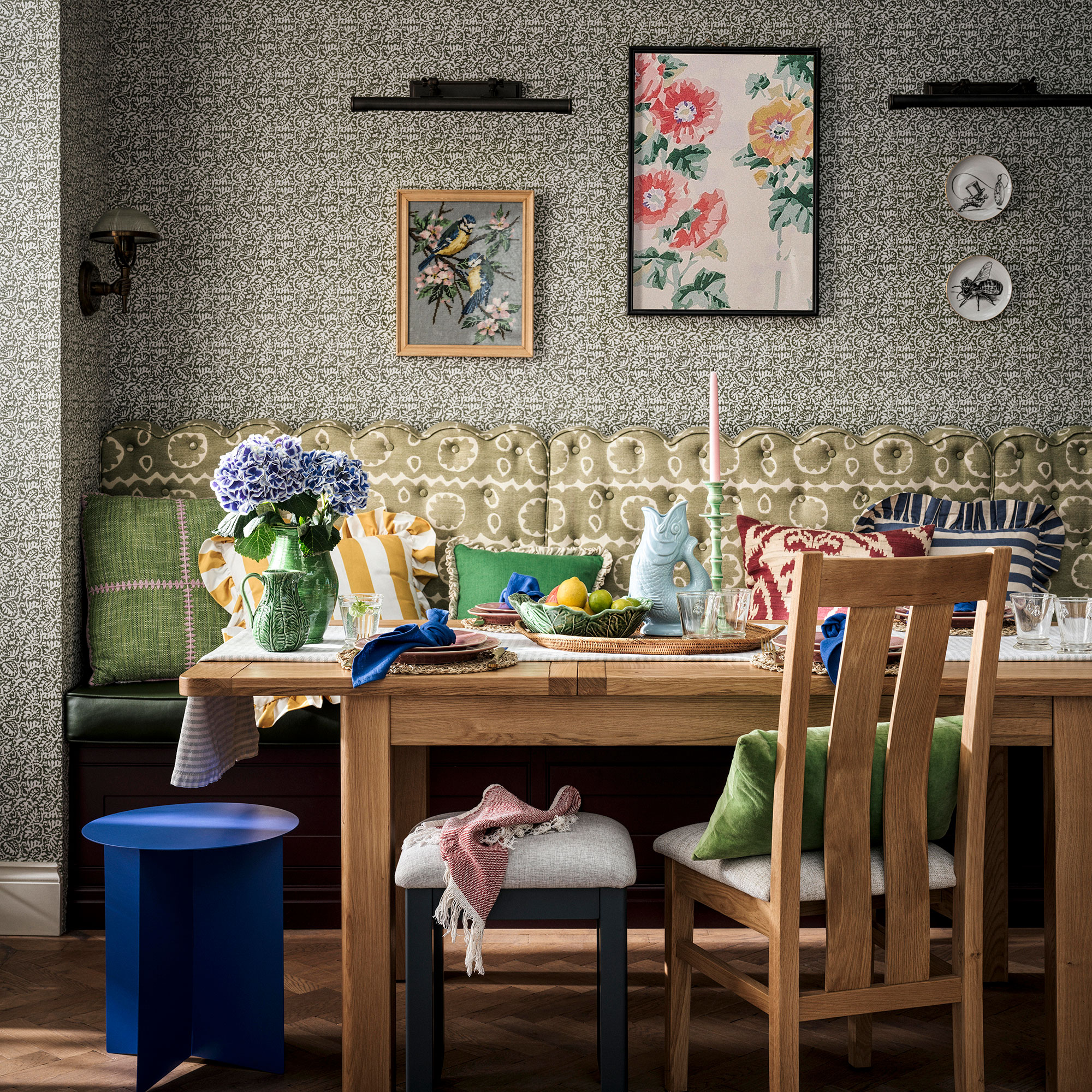 Kitchen diner with wooden table, patterned wallpaper and banquette cushions