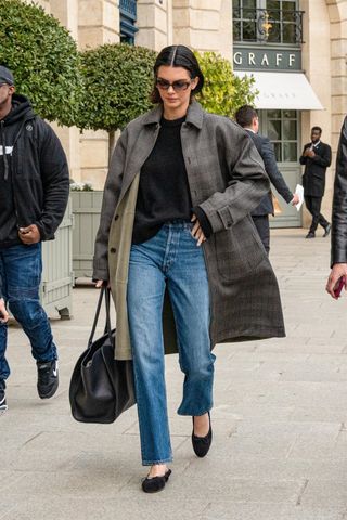 Kendall Jenner wears a plaid coat with jeans and ballet flats