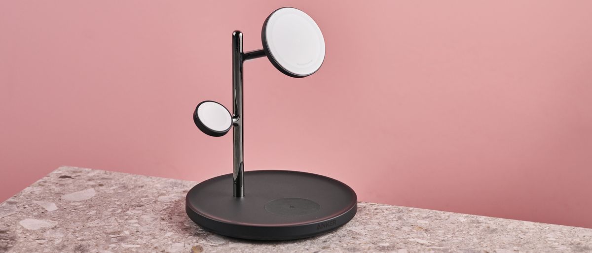 The Anker MagGo Charging Station 3-in-1 stand sits facing slightly to the right. It is sitting on a stone-effect surface with a pink background.